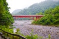 View of red bridge over river in Taroko National Park, Taiwan. Taroko Gorge surrounded by tropical green forest and rocks. Royalty Free Stock Photo