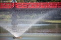 View of the red bridge through the slender jets of water. Tennoji Park. Osaka. Japan