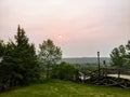 A view of the red sun through smoky hazy orange and brown sky in a park downtown Edmonton, Alberta, Canada