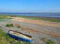 View of the ribble estuary in lancashire with a small fishing boat on the river and and old derelict rowing boat beach Royalty Free Stock Photo