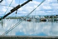View through rigging of fishing boats across estuary to boats in marina