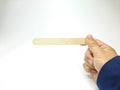 View of right hand holding wooden ice cream stick isolated on white background. Royalty Free Stock Photo