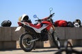 Red and white enduro motorcycle near the granite fence on a sunny day