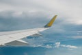 View of right wing from window of airplane flying up in the sky, through clouds in atmosphere. Plane in flight. Up in the air.