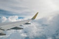 View of right wing from window of airplane flying up in the sky, through clouds in atmosphere. Plane in flight. Up in the air.