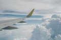 View of right wing from window of airplane flying up in the sky, through clouds in atmosphere. Plane in flight. Up in the air.