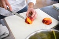 view of peach sliced on cutting board and male chef hand with knife nearby