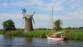 View of the river Ant Norfolk with vintage sailing boat and wind pump.