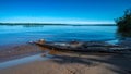 View from the river bank to the water surface with the trunk of an old tree in the foreground Royalty Free Stock Photo