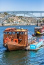 View of river Douro, with touristic tour boats on docks, D. Luis bridge and Porto city as background