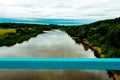 View of river and fields with haystacks, trees and nature over the railing of the old blue bridge Royalty Free Stock Photo