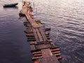 View of the river with a lonely fishing boat moored to an old wooden pier. Vintage style Royalty Free Stock Photo