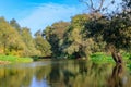 View of river surface with green trees on shores on a background of blue sky. River landscape in sunny autumn morning Royalty Free Stock Photo