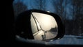 View of the road behind trough a side mirror of a car. It is winter time. View of the winter road in the rearview mirror Royalty Free Stock Photo