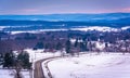 View of road through snow-covered fields and distant mountains, Royalty Free Stock Photo