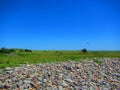 Seaside meadow with rock pile and kiteboarder in the distance Royalty Free Stock Photo