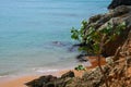 View from the rocky cliff of sea waves crashing into orange sandy beach in La Guajira, Colombia