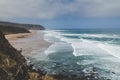 View of rocky coast of the Atlantic Ocean and beach with large waves. Surfer on the ocean coast with surfboard. Praia Grande. Sin