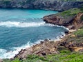 View of the rocky shore of the blue-turquoise sea bay with white wave crests