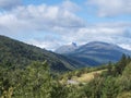 View on Romsdalen valley from the road E136 with snow capped peaks of mountains, green forest and small red yellow house. Blue sky Royalty Free Stock Photo