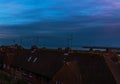 view of the roofs of buildings in a seaside town, in the background stone pier and ocean, sunset Royalty Free Stock Photo