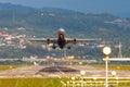 View of the runway of the airport, and a take-off plane against the background of mountains and houses