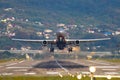 View of the runway end of the airport, and a take-off plane against the backdrop of mountains and houses