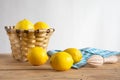 View of rustic table with basket with lemons, cloth and wooden juicer, white background, horizontal, Royalty Free Stock Photo