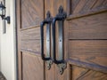 Angled view of rustic, wooden doors with black iron handles on a light colored building Royalty Free Stock Photo