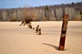 View of the rusty remains of an iron fence on the sandy bank of the river.