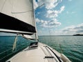 View on a sailboat bow of white sailing yacht on a lake during sailing in a summer sunny day