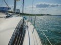 View on a sailboat bow of white sailing yacht on a lake during sailing in a summer sunny day