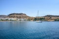 View of sailing boat near Haraki beach with ruin of castle on hilltop Rhodes, Greece