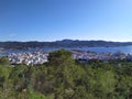 View of San Antonio harbor from wooded hills, sea and mountains in background, houses and hotels in San Antonio, Ibiza