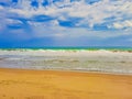 View from sand beach to wavy sea and cloud sky. Royalty Free Stock Photo