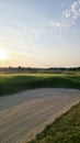 View of a sand bunker on a golf course, with green turf and the setting sun in the background. Royalty Free Stock Photo