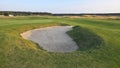 View of a sand bunker on a golf course, with green turf and the setting sun in the background. Royalty Free Stock Photo
