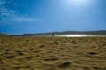 View of sand surface against blue sky background, with clouds, sun halo, reflection on ocean water. Unique natural areas Royalty Free Stock Photo