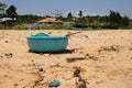 View on a sandy beach near to fishing village with a lot of garbage. Pollution of a coastline Royalty Free Stock Photo