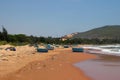 View on a sandy beach near to sea and fishing village with a lot of garbage. Pollution of a coastline. Royalty Free Stock Photo