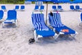 View of the sandy Miami beach with sun loungers covered with beach towels secured with clips and beach slippers left behind. Royalty Free Stock Photo