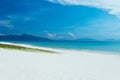 View of sandy sea beach. Calm waves, foam. Blue sky with white clouds. An empty long beach, ocean and mountain background Royalty Free Stock Photo