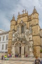 View of the Santa Cruz Monastery front facade, romanesque and gothic style, with tourists on street , a National Monument in