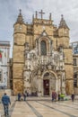 View of the Santa Cruz Monastery front facade, romanesque and gothic style, with tourists on street , a National Monument in