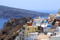 View on Santorini looking at colourful buildings dome churches with mountain and sea in the background.