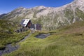 View of the Scaletta hut near the Greina Pass in Blenio, Switzerland. There is a trail in the foreground, and two hikers