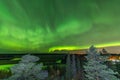 View from scandinavian hill to bright green aurora lights almost on the whole sky over tree tops in Sweden, river, clear skies Royalty Free Stock Photo