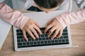 View of schoolkid using laptop while sitting at desk and doing homework