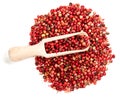 View of scoop on pile of pink peppercorns on white