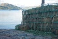 View of the sea beyond weathered prawn traps piled on a dock in western Scotland